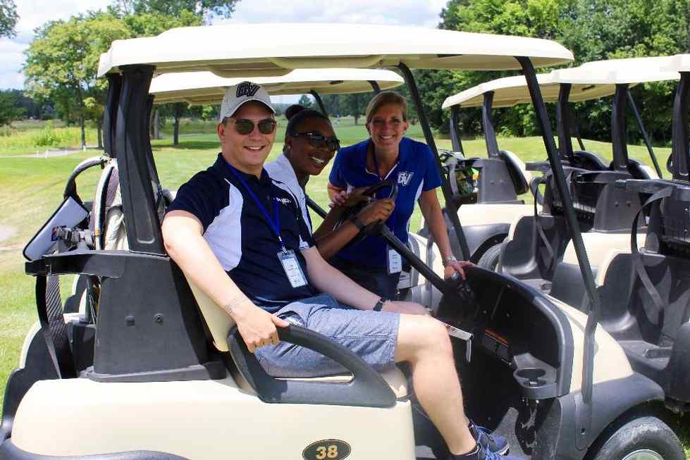 Golf cart with two golfers, one looking on